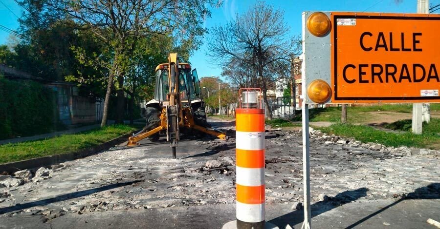vista de la calle siendo taladrada por una retroexcavadora con martillo neumático y un cartel de calle cerrada