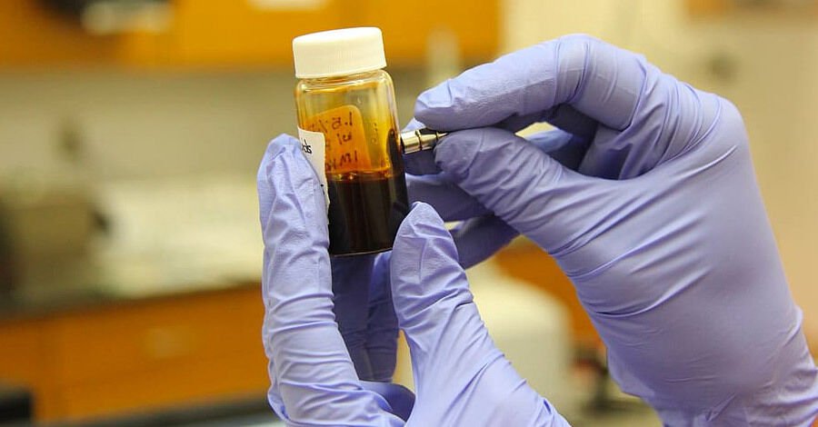 manos con guantes de látex etiquetando un frasco con una muestra de sangre