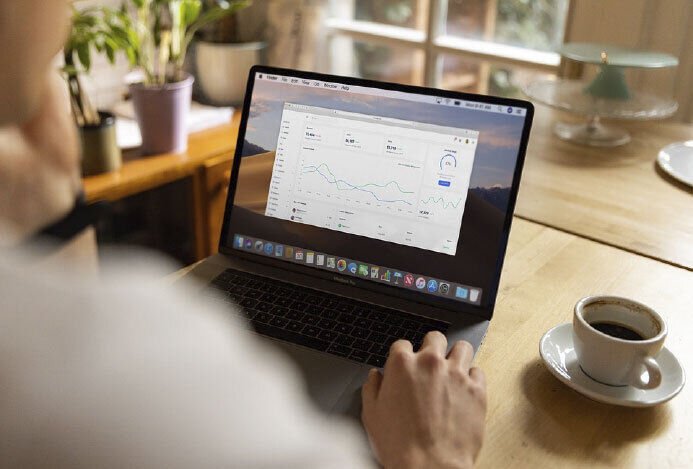 una persona vista desde atrás sentada en un escritorio trabajando con un laptop